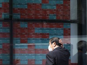 FILE - A person looks at an electronic stock board showing Japan's stock princes at a securities firm Tuesday, April 2, 2024, in Tokyo. Asian shares mostly declined Friday, April 5, after a U.S. Federal Reserve official said the central bank might not deliver any of the interest rate cuts that Wall Street has been banking on this year, citing concerns about inflation.