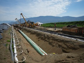 Workers lay pipe during construction of the Trans Mountain pipeline expansion on farmland, in Abbotsford, B.C., on Wednesday, May 3, 2023. The Trans Mountain oil pipeline expansion will go into commercial service on May 1.