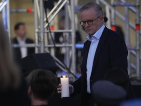 Australian Prime Minister Anthony Albanese carries a candle during a candlelight vigil at Sydney's Bondi Beach to remember victims of a knife attack at a nearby shopping mall, Australia, Sunday, April 21, 2024. An assailant was shot and killed by a police officer on April 13, after he stabbed six people to death and wounded more than a dozen others in an attack that police believe targeted women.