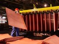 A worker handles newly formed copper cathode sheets in a warehouse at the KGHM Polska Miedz SA copper smelting plant in Glogow, Poland, on Tuesday, March 9, 2021.