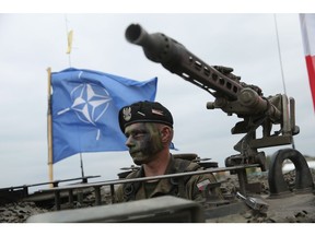 ZAGAN, POLAND - JUNE 18: A soldier of the Polish Army sits in a tank as a NATO flag flies behind during the NATO Noble Jump military exercises of the VJTF forces on June 18, 2015 in Zagan, Poland. The VJTF, the Very High Readiness Joint Task Force, is NATO's response to Russia's annexation of Crimea and the conflict in eastern Ukraine. Troops from Germany, Norway, Belgium, Poland, Czech Republic, Lithuania and Belgium were among those taking part today.