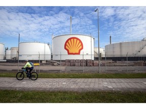 A cyclist passes oil silos at a Shell Plc refinery in Rotterdam, Netherlands.