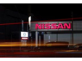 Vehicles leave light trials as they pass a Nissan Motors Co. dealership.