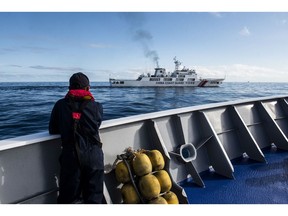 A Philippine Coast Guard personnel looks out at a China Coast Guard ship during a resupply mission for the BRP Sierra Madre, in the Second Thomas Shoal in the disputed South China Sea, on Friday, Nov. 10, 2023. Both China and the Philippines lay claims over the shoal while at least three other neighbors also claim the larger Spratly Islands chain it nestles in. Photographer: Lisa Marie David/Bloomberg