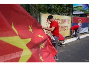 A worker attaches a large national flag of China to fencing ahead of the state visit of China's President Xi Jinping, in Belgrade, Serbia, on Tuesday, May 7, 2024.  Photographer: Oliver Bunic/Bloomberg