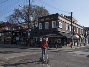 A new report lays out how an innovative funding model for community groups could be scaled up. A man scooters down an empty Kensington Market in Toronto, Wednesday, April 7, 2021.