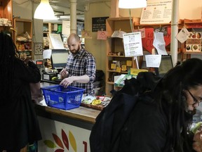 Store manager Zachary Weingarten helps members cash out at the Karma Co-op Food Store in Toronto, Friday, March 15, 2024. The co-op focuses on local, organic and ethically produced foods, with many products available in bulk for zero-waste shoppers.