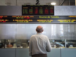 Investors mulling where to park their money have a choice to make: whether to go with a traditional financial adviser or a robotic one. A man watches the financial numbers on the digital ticker tape at the TMX Group in Toronto's financial district, Friday, May 9, 2014.