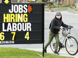A cyclist moves past a jobs advertisement sign in Toronto.