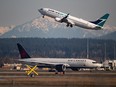 An Air Canada flight departing for Toronto, bottom, taxis to a runway as a Westjet flight bound for Palm Springs takes off at Vancouver International Airport in Richmond, B.C.