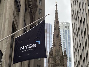 FILE - A flag hangs from the side of the New York Stock Exchange is on Thursday, May 16, 2024, in New York. Trinity Church appears in the background.