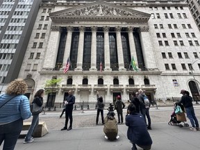 FILE - Tourists gather near the New York Stock Exchange on May 16, 2024, in New York. Shares retreated in Europe and Asia on Friday, May 24, 2024, after unexpectedly strong reports on the U.S. economy raised the possibility that interest rates may stay painfully high.