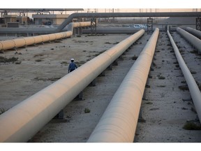 An employee walks along transport pipes leading to oil storage tanks at the Juaymah tank farm at Saudi Aramco's Ras Tanura oil refinery and oil terminal in Ras Tanura, Saudi Arabia, on Monday, Oct. 1, 2018. Saudi Aramco aims to become a global refiner and chemical maker, seeking to profit from parts of the oil industry where demand is growing the fastest while also underpinning the kingdom's economic diversification. Photographer: Simon Dawson/Bloomberg