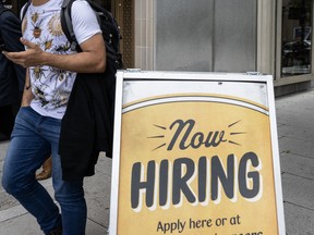 People walk past a restaurant, with a hiring sign outside, in Washington, DC on Oct. 5, 2023.
