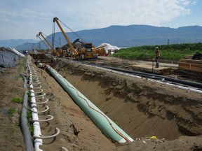 Workers lay pipe during construction of the Trans Mountain pipeline expansion on farmland, in Abbotsford, B.C. on May 3, 2023.