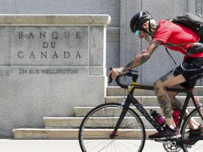 A cyclist makes their way past the Bank of Canada in Ottawa on July 11, 2023.