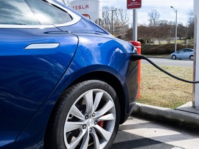 A Tesla Model S sedan is plugged into a Tesla Supercharger electrical vehicle charging station in Falls Church, Virginia, February 13, 2023.