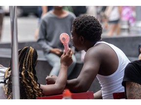 Visitors use a handheld fan during a heat wave in New York, US, on Thursday, July 27, 2023. New York City and the Northeast are in for their hottest day of the year as oppressive temperatures descend on the eastern and central US, affecting about half the country's population.