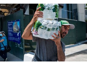A vendor carries a case of water at Coney Island on a hot afternoon, on June 22.