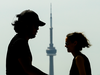 The CN Tower sticks up between two people walking