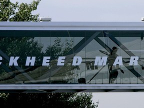 FILE - A man walks past a Lockheed Martin logo as he walks through a section of the company's chalet bridging a road at Farnborough International Airshow in Farnborough, southern England, July 19, 2006. China says it has banned a number of business units of American aviation maker Lockheed Martin and three of its executives over arms deals with Taiwan, the self-ruling island it claims as its own territory.