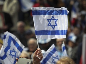 A flag of Israel is held aloft at Place du Canada in Montreal during Yom Ha’atzmaut celebrations, 2019.