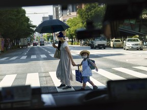 FILE - A pedestrian crossing a street with a child is seen through a taxi window in Tokyo, Monday, July 19, 2021. Japan's birth rate fell to a new low for the eight straight year in 2023, according to Health Ministry data released on Wednesday, June 5, 2024.
