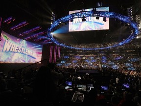 FILE - A WrestleMania sign hangs over the crowd during a WWE event, Monday, March 6, 2023, in Boston. In an announcement Monday, June 24, 2024, WWE and Indiana Sports Corp. are teaming up to bring the sports entertainment company's three largest stadium events, Royal Rumble, SummerSlam and WrestleMania, to Indianapolis.
