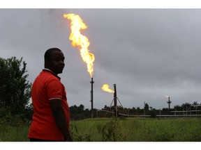 A man looks on as flares burn from pipes at an oil flow station operated by Nigerian Agip Oil Co. Ltd. (NAOC), a division of Eni SpA, in Idu, Rivers State, Nigeria, on Monday, Sept. 28, 2015. Nigeria's daily output of about 2 million barrels of oil makes it Africa's largest producer. Photographer: Bloomberg/Bloomberg