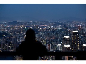 A woman is silhouetted as she looks at a city skyline from an observation deck of Woomyeon mountain at dusk in Seoul, South Korea, on Thursday, July 9, 2020. South Korea's government is preparing new regulations to curb excessive house price gains that have fueled public discontent over inequality and property speculation. Photographer: SeongJoon Cho/Bloomberg