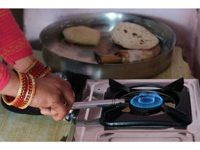 A woman lights a stove connected to an Indian Oil Corp. Indane brand liquefied petroleum gas (LPG) cylinder at a village home in Greater Noida, Uttar Pradesh, India, on Monday, Feb. 22, 2021. Provisions for LPG cooking fuel subsidies, launched in 2016 by the Modi government offering cash rebates for purchasing an LPG connection and a loan for the first canister of the fuel and stove, were halved in the federal budget for the fiscal year ending March 2022 to 124.8 billion rupees ($1.7 billion) from 255 billion rupees a year earlier.