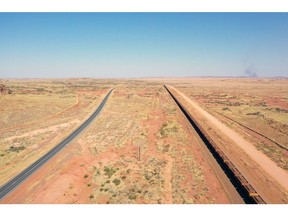 Sebuah kereta api yang membawa bijih besi berjalan di sepanjang jalur kereta menuju fasilitas pelabuhan Rio Tinto Group di Karratha, Australia Barat.