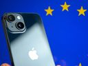 This photograph shows a hand-held smartphone with the Apple company logo and the European Union logo in the background, in Brussels on Sept. 9, 2024.