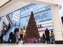People pass a large Christmas tree as they go shopping on Christmas Eve at a mall in Ottawa, Ont., 2020.