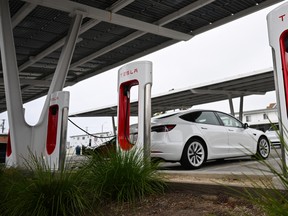 Tesla electric vehicles charge on EV charging stations beneath solar panels at a Tesla Supercharger location in Santa Monica, Calif. on May 15, 2024.
