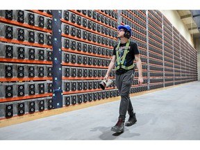 Seorang teknisi berjalan di dekat rig penambangan cryptocurrency di fasilitas Bitfarms Bunker di Sherbrooke, Quebec, Kanada, pada Senin, 9 September 2024.