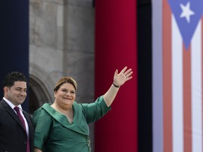Jenniffer Gonzalez Colon waves alongside her husband Jose Yovin Vargas during her swearing-in ceremony as governor outside the Capitol in San Juan, Puerto Rico, Thursday, Jan. 2, 2025.