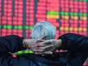 An investor looks at a screen showing stock market movements at a securities company in Hangzhou, in eastern China's Zhejiang province on Feb. 8, 2024.