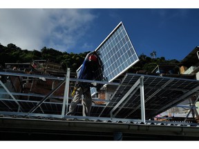 Seorang pekerja memasang panel surya di Rio de Janeiro pada Maret 2023.