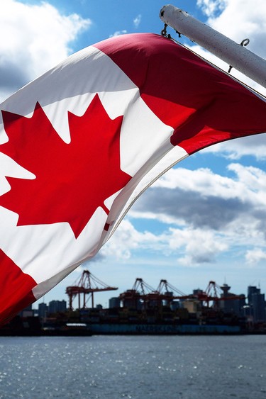A Canadian flag flies in front of the Vancouver skyline.
