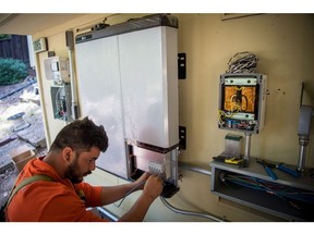 A worker installs a solar battery on a home in Lafayette, California. Photographer: David Paul Morris/Bloomberg