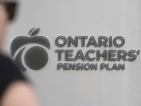 A person walks past signage for The Ontario Teachers Pension Plan in Toronto’s Financial District on Sept. 16, 2024.