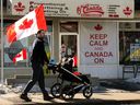 A man makes his way past flags and a Keep Calm And Canada On sign outside O'Canada Gear, in Edmonton, March 8, 2025.