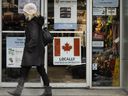A person walks past a pet store with a Canadian flag with writing stating 'locally owned and operated' in Toronto, Ont.
