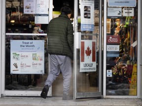 A person walks past a pet store with a Canadian flag and writing stating 'locally owned and operated' in Toronto.
