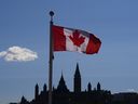 Parliament Hill is located under the Canadian flag in Queens, Canada.