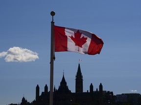 Parliament Hill is viewed below a Canadian flag in Gatineau, Que.
