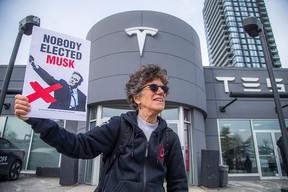 A woman protests outside a Tesla showroom in Ottawa.