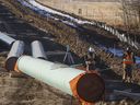 Workers survey around pipe to start of right-of-way construction for the Trans Mountain Expansion Project, in Acheson, Alta., Tuesday, Dec. 3, 2019.