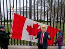 Toronto resident Douglas Bloomfield and his son Phoenix were on vacation in Washington, holding Canadian flags and hockey sticks to show their support for Canada as they headed to the front of the White House on March 13, 2025, with another visitor wearing President Donald Trump's mask.